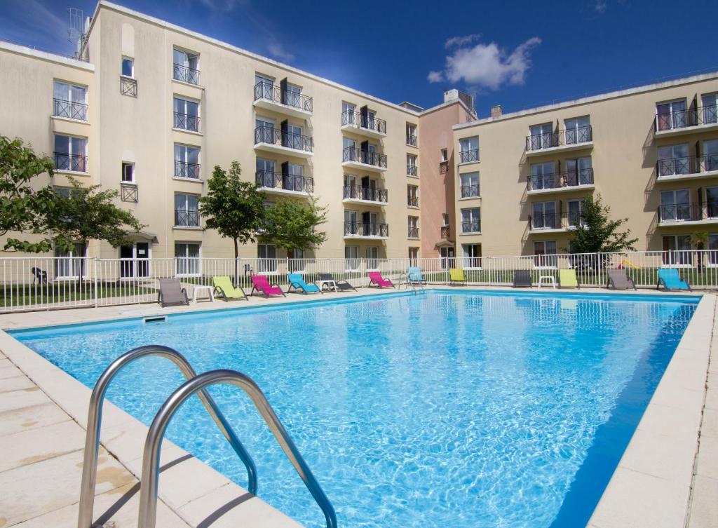 - une piscine en face d'un immeuble dans l'établissement Résidence Du Parc Val d'Europe, à Montévrain