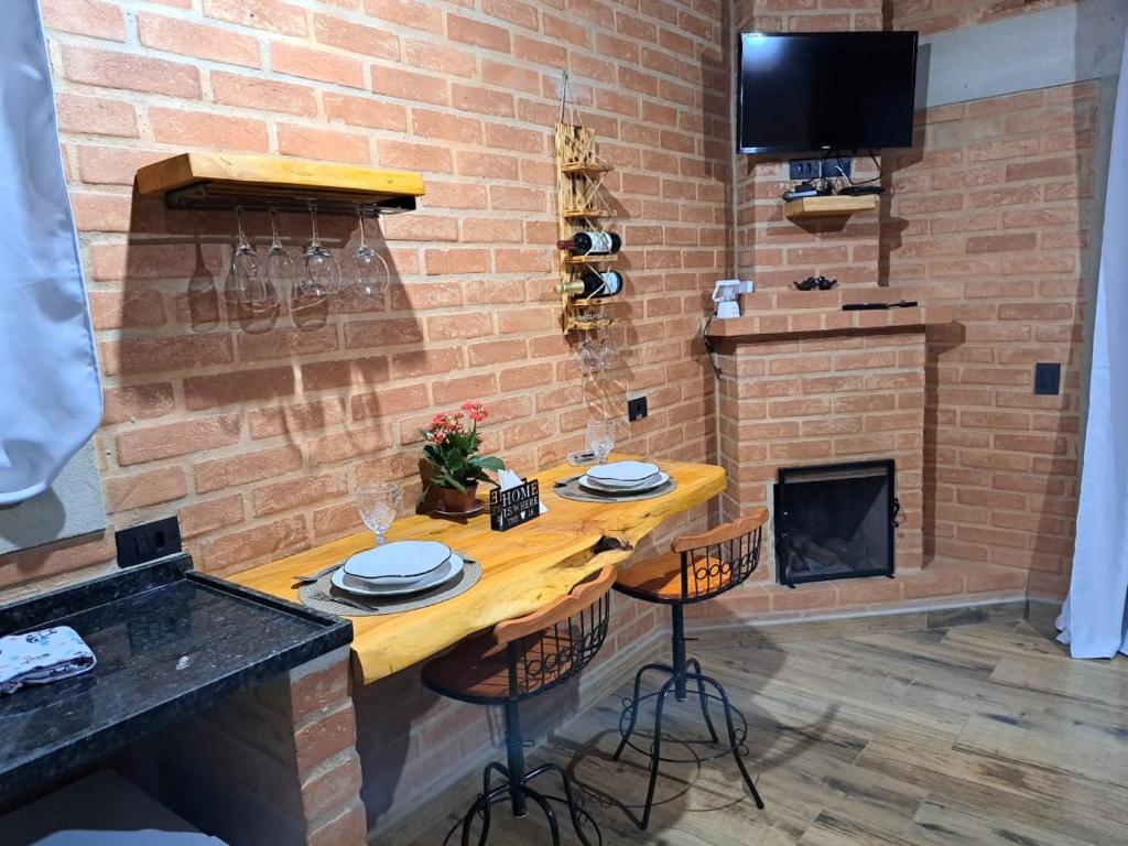 a brick wall with a table and a fireplace at Chalé Black Touch in Santo Antônio do Pinhal
