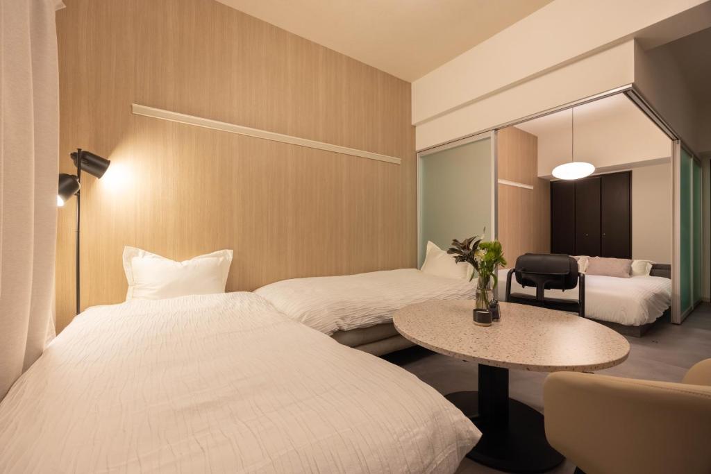a hotel room with two beds and a table at Rintow Nagoya Takaoka STAY in Nagoya
