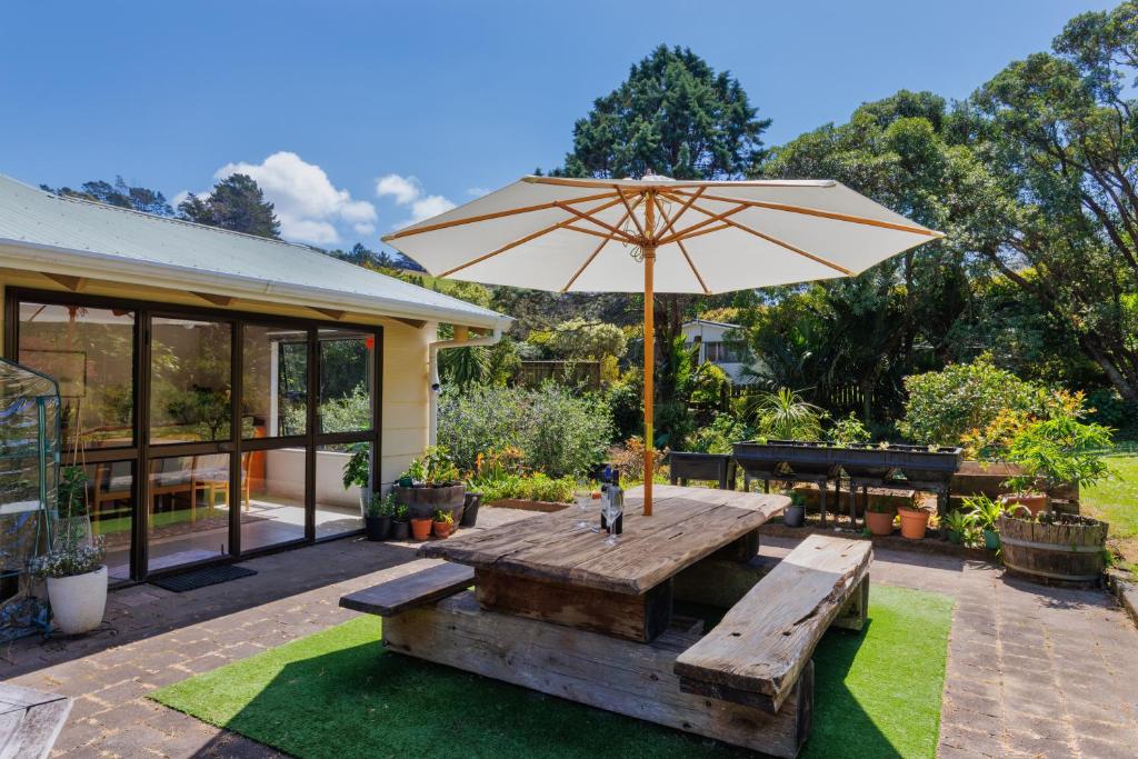 a wooden table with an umbrella and benches at Palm Beach Waiheke Tranquil B&B in Ostend