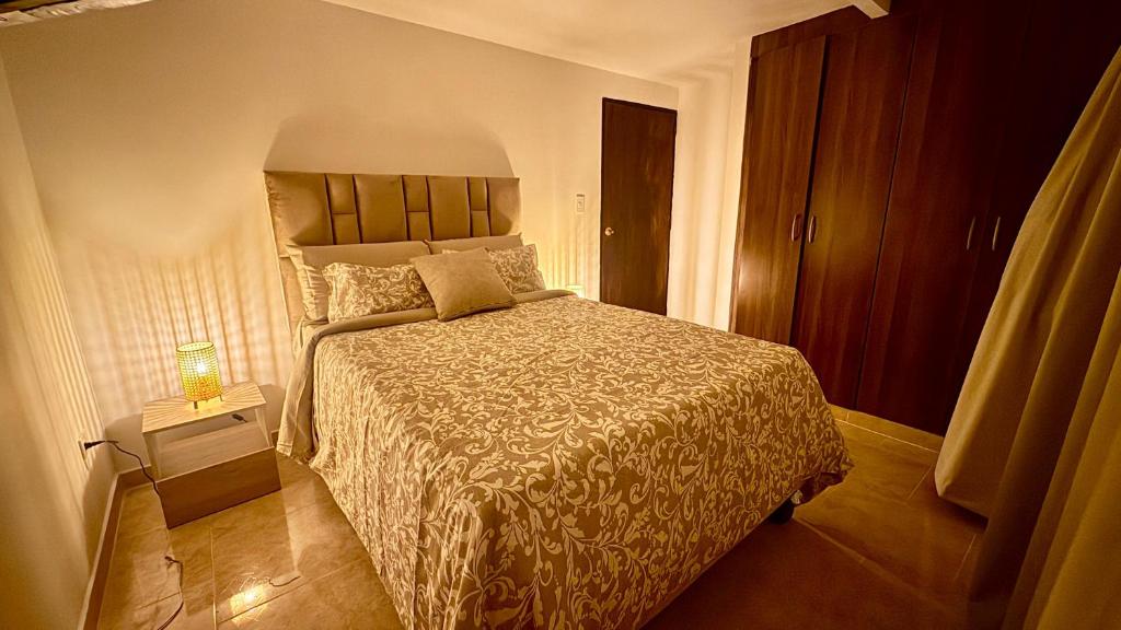 a bedroom with a bed and a lamp on a table at Casa Bella Apartamentos in Cali