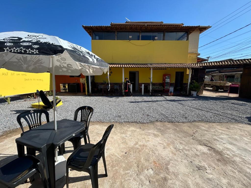 Una mesa y sillas con una sombrilla frente a un edificio. en Pousada Marina bonita Rasa, en Búzios