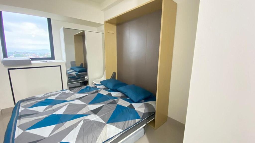 Un dormitorio con una cama con almohadas azules y una ventana. en Apartment Bandaraya Tallasa City 11B21 By Millpro, en Patjinongong