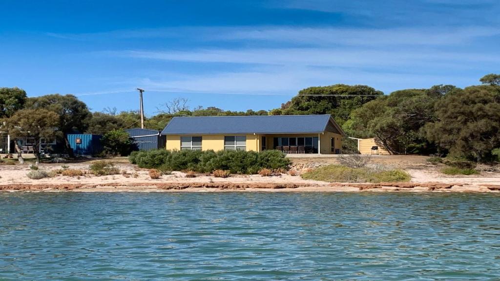 a yellow house on the shore of the water at The Beach House - Spectacular Location - Privacy - Right On The Beach in Coffin Bay