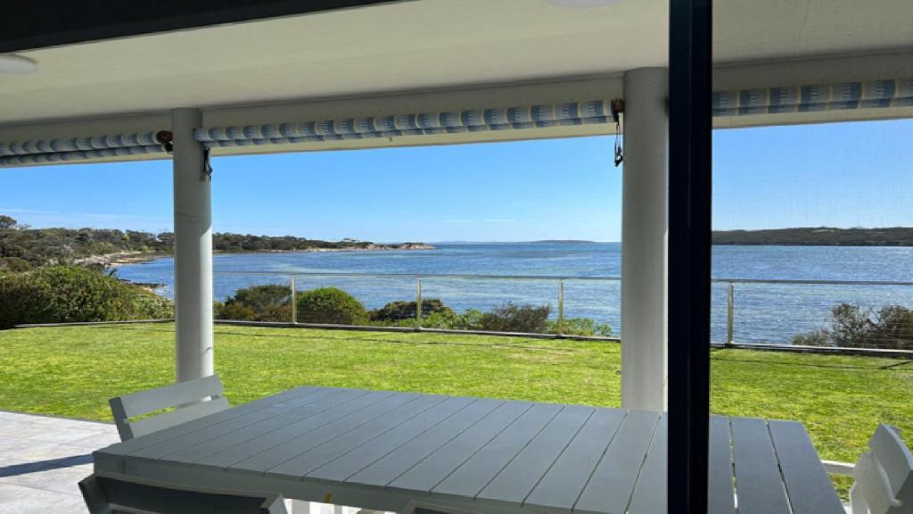 a porch with a table and a view of the ocean at Wrightaway in Coffin Bay