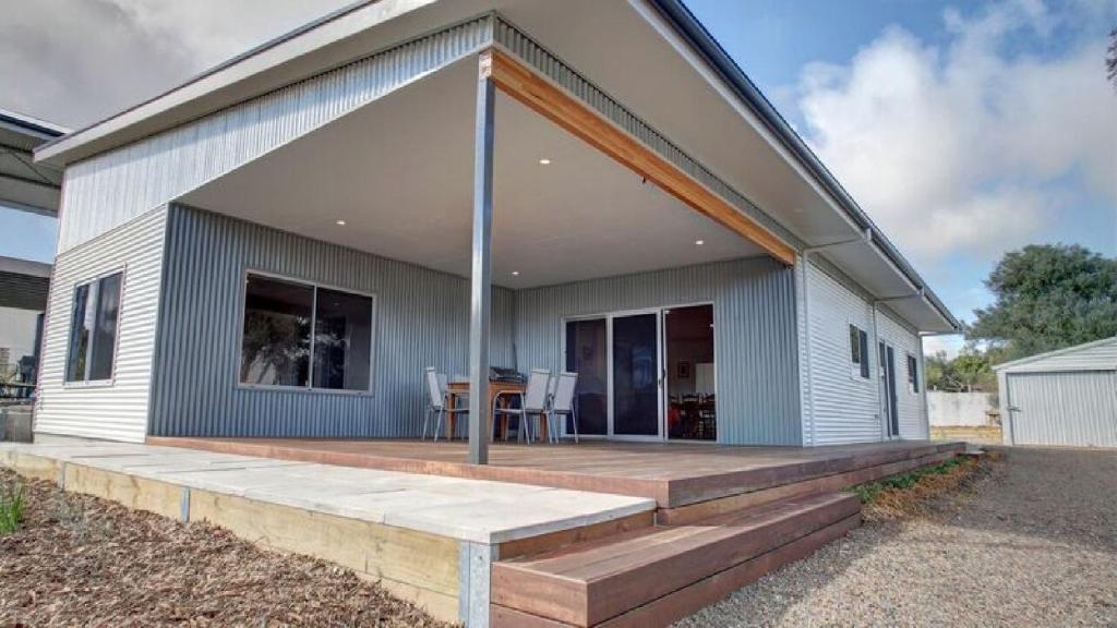 a house with a wooden deck in front of it at Grey On The Bay in Coffin Bay