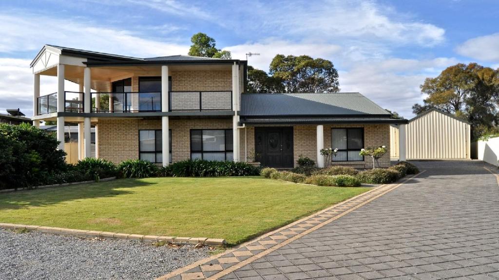 a brick house with a lawn in front of it at Coffin Bay Retreat in Coffin Bay
