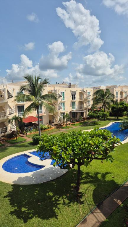 a view of a resort with a tree in the foreground at Marina Diamante Victory in Acapulco