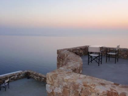 a table and chairs sitting next to the water at Villa Kalamiotissa in Anafi