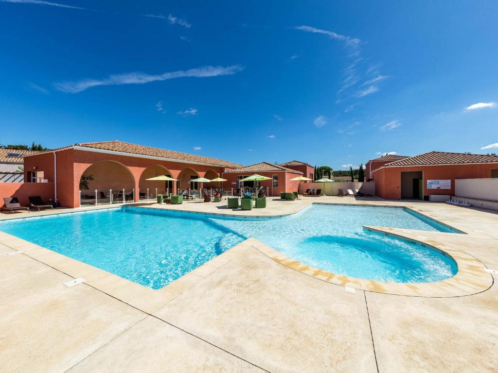 a large swimming pool in a courtyard with a building at Terres de France - Le Domaine de Bacchus in Saint-Christol