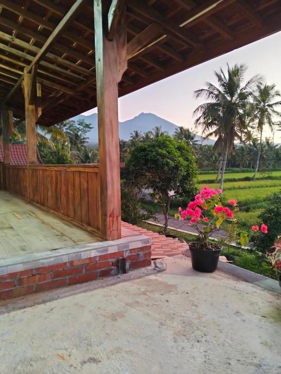 a porch of a house with flowers and a palm tree at Nataqueen Bungalows in Tetebatu