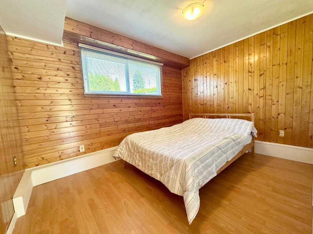 a bedroom with a bed in a room with wooden walls at Peaceful place with Living Room, Kitchen and Washing Machine near YVR Airport, Transit and Shopping Mall in Richmond