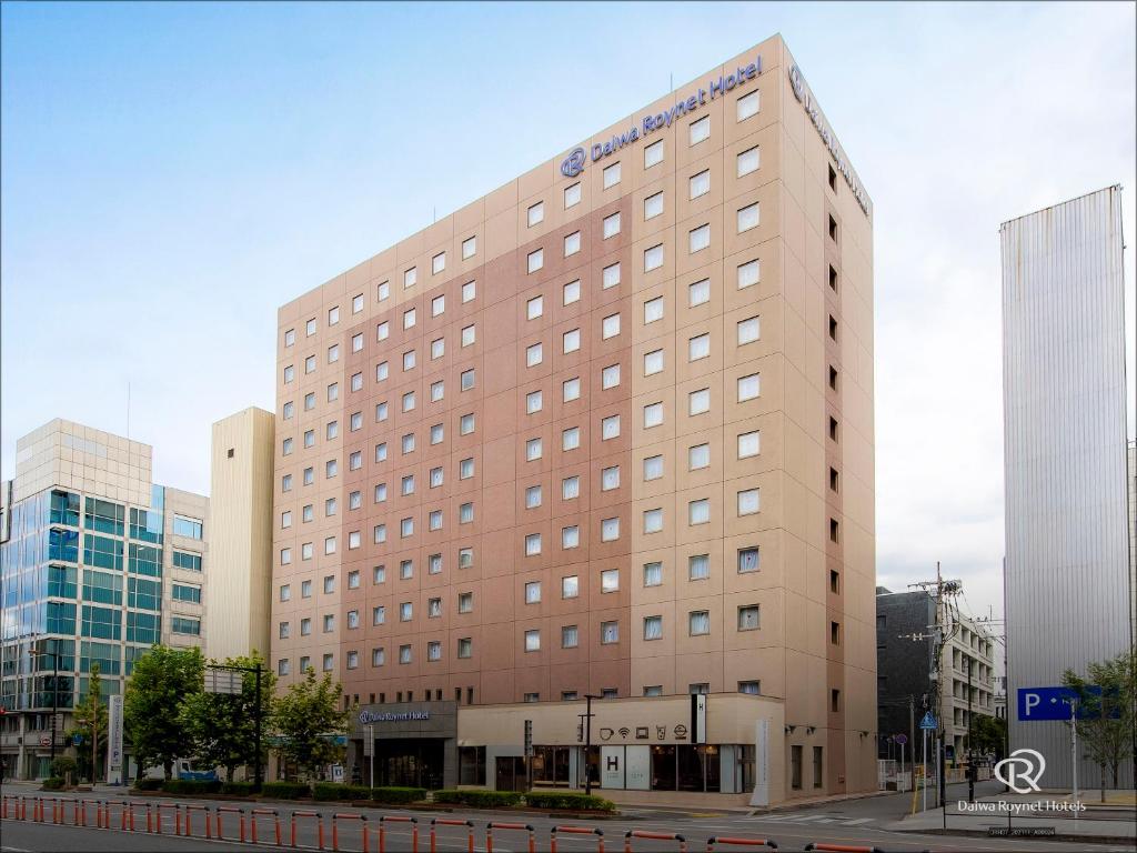 a large brown building in front of some buildings at Daiwa Roynet Hotel Oita in Oita