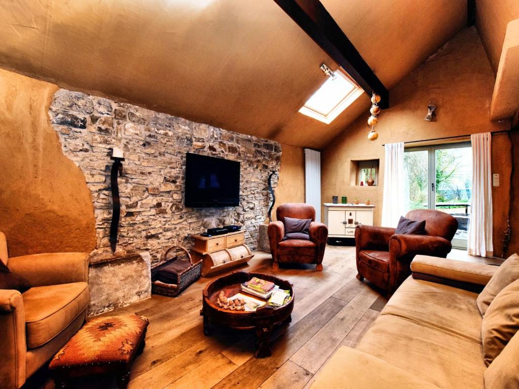 ein Wohnzimmer mit einer Couch und einer Steinwand in der Unterkunft Relaxing Retreat Near Forests in Oppagne