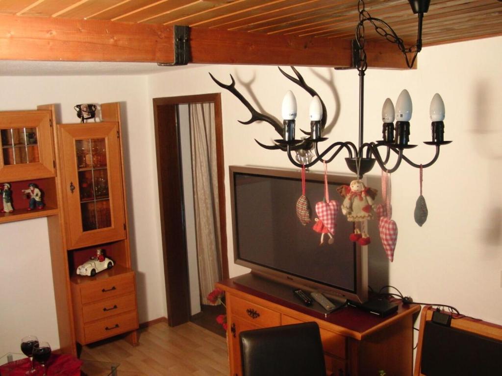 a living room with a television and a chandelier at Ferienwohnung Anne in Sankt Ulrich am Pillersee