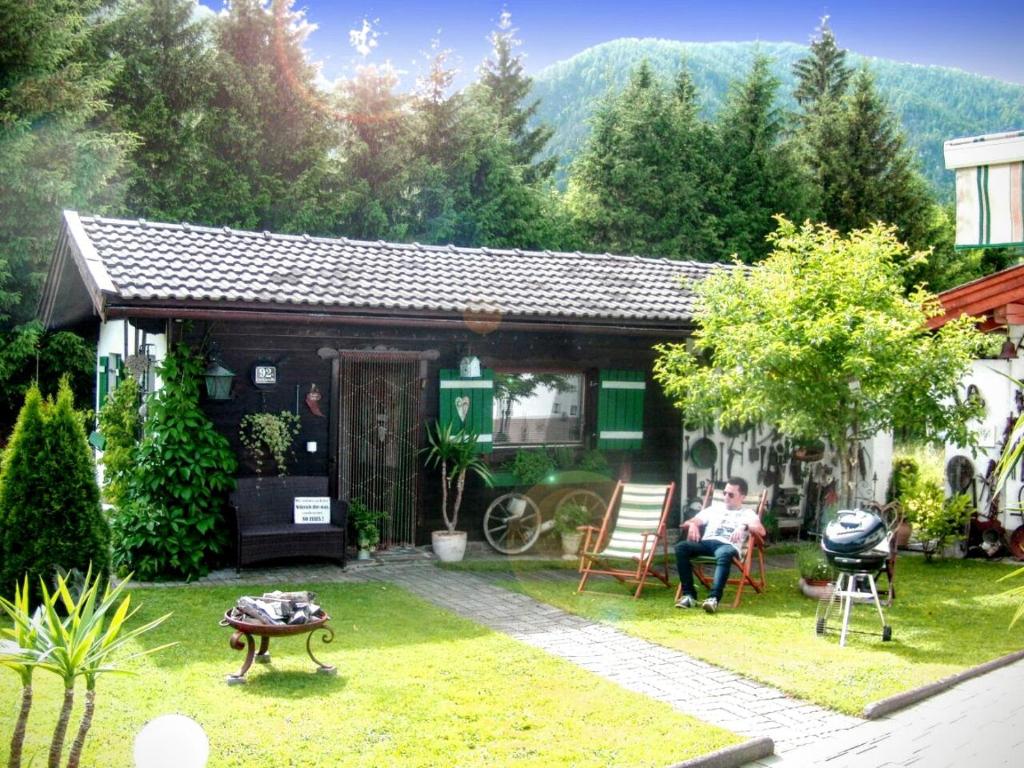 een man in een stoel voor een huis bij Ferienwohnung Anne in Sankt Ulrich am Pillersee