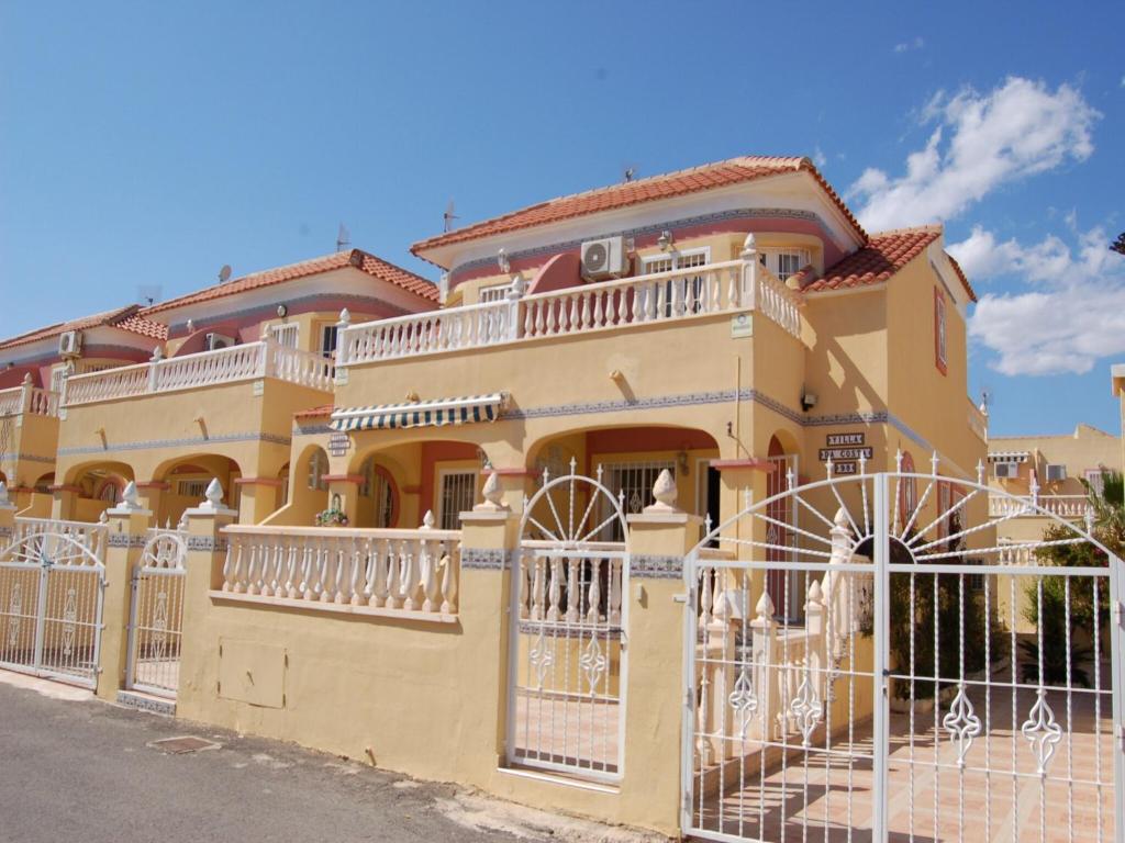 een geel huis met een hek ervoor bij Sunny Stay, Orihuela Costa in Villamartin