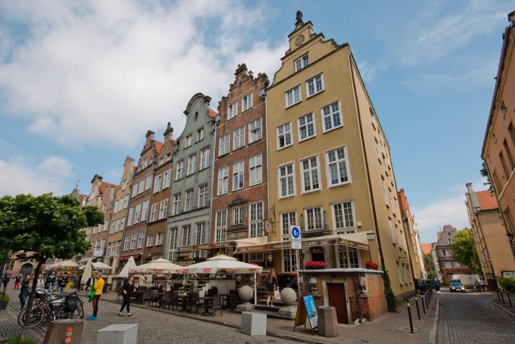 un grupo de edificios en una calle con mesas y sombrillas en Apartamenty Gdańsk EU - Apartamenty Przy Piwnej II, en Gdansk