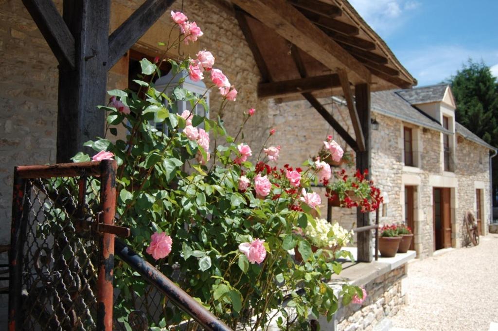 a fence with pink roses in front of a building at Chambres et table d'hôtes La Panacée in Cuzance
