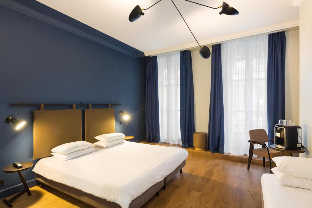 - une chambre avec un grand lit blanc et des murs bleus dans l'établissement Hôtel Silky by HappyCulture, à Lyon