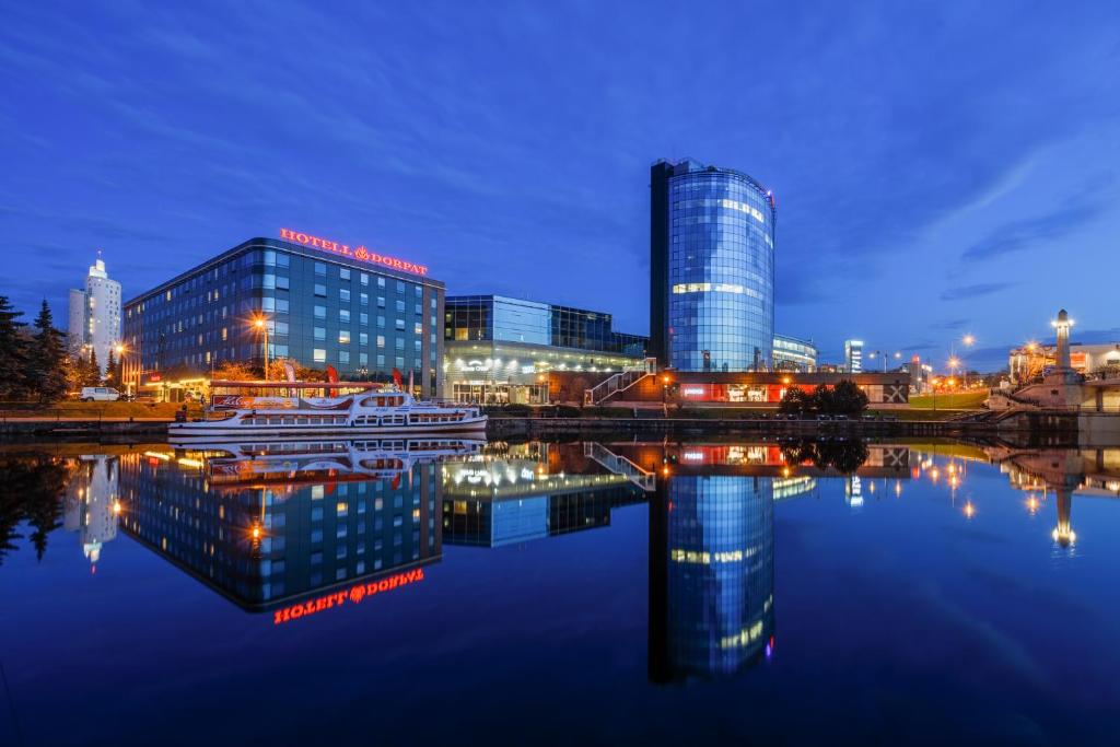 a city at night with a reflection in the water at Dorpat Hotel in Tartu