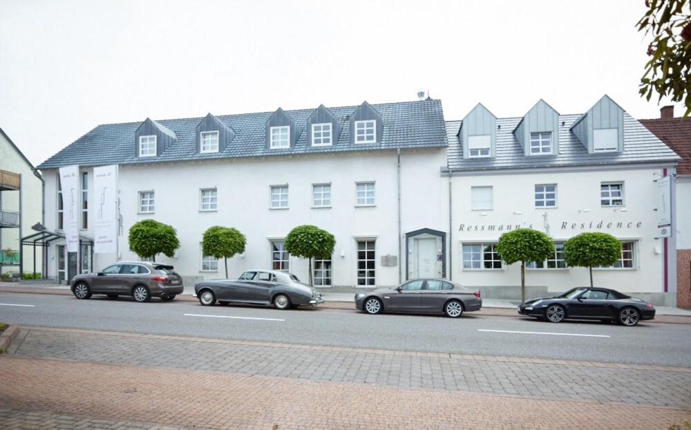 un groupe de voitures garées devant un bâtiment blanc dans l'établissement Ressmann`s Residence, à Kirkel