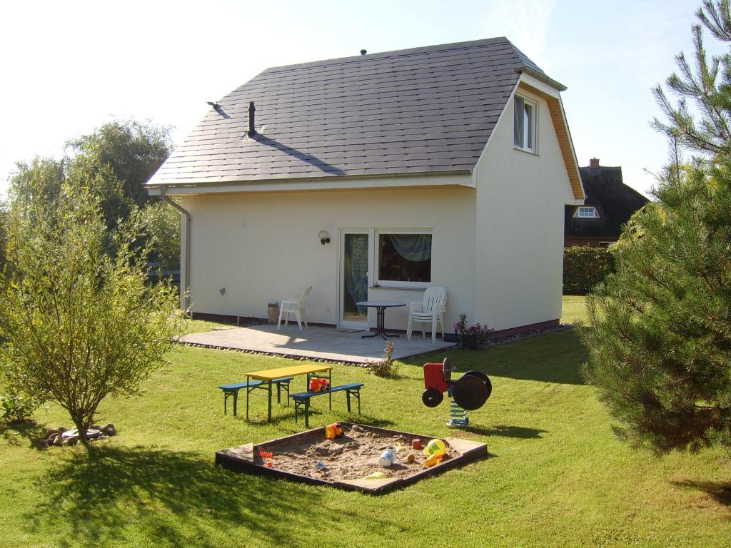 ein kleines weißes Haus mit einem Sandkasten im Hof in der Unterkunft MaRa-Ferienhaus in Dranske