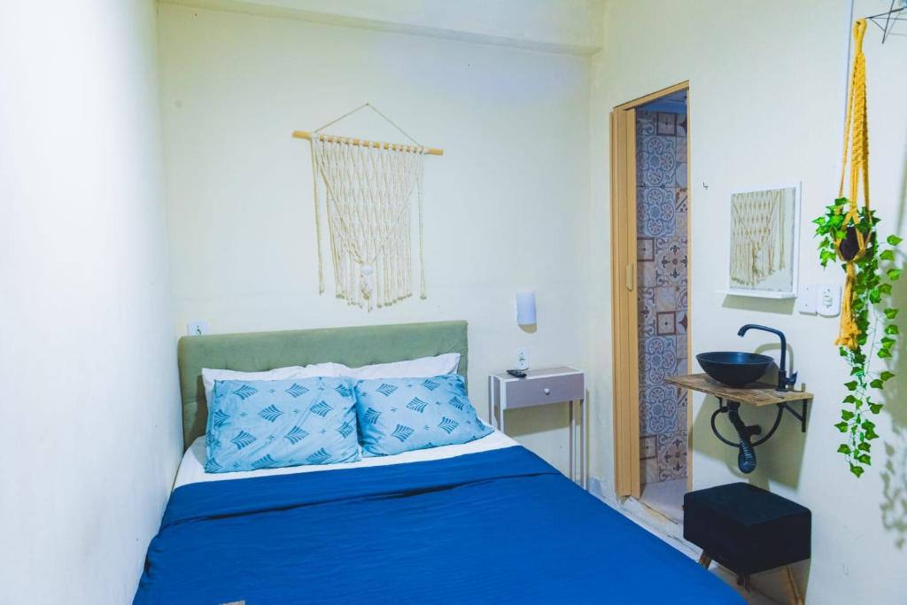 a bedroom with a blue bed in a white room at Suite dos Anjos com Cozinha 150m da Praia in Arraial do Cabo