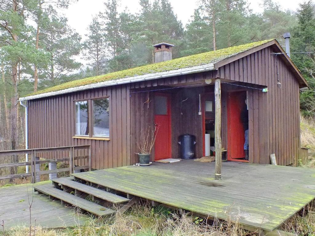 a small building with a deck and a red door at 5 person holiday home in FARSUND-By Traum in Helle