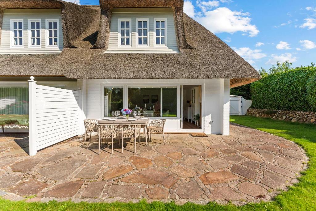 a patio with a table and chairs in front of a house at Ferienhüs Keitumliebe in Keitum