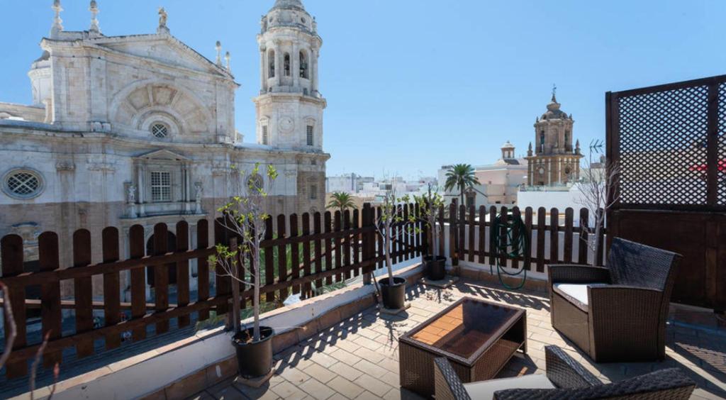 a balcony with chairs and a fence and a building at Atico Cadiz in Cádiz