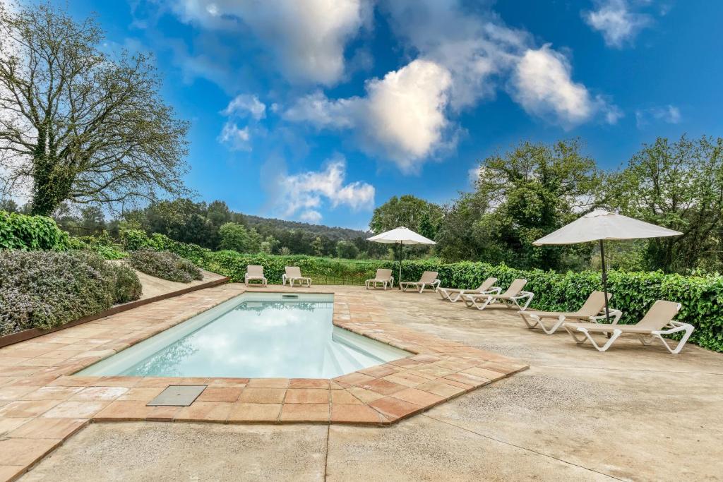une piscine avec chaises et parasols dans l'établissement Mas Tarres L'alzina Madremanya, à Madremanya