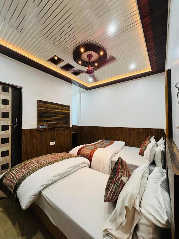 a bedroom with three beds and a ceiling at S R Hotel in Varanasi