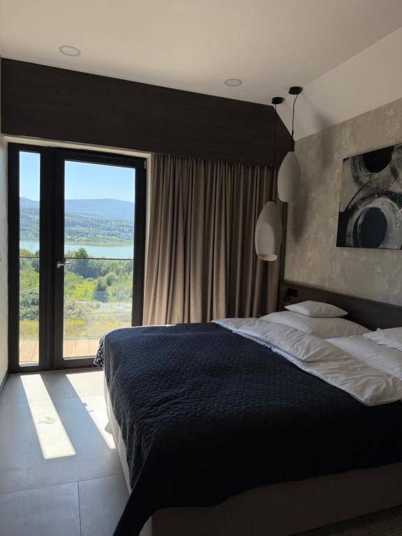 a bedroom with a large bed and a large window at Lake Chill Sosnówka panorama na góry i zalew in Sosnówka