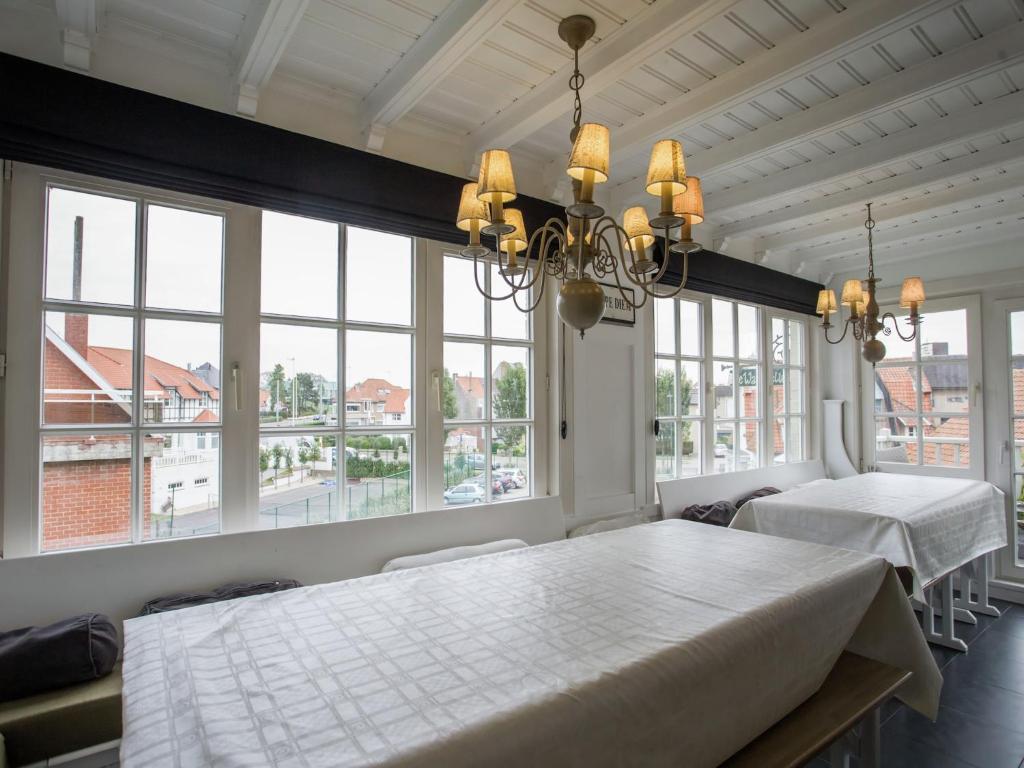 een eetkamer met een tafel en grote ramen bij Holiday Home in Koksijde near Beach in Koksijde