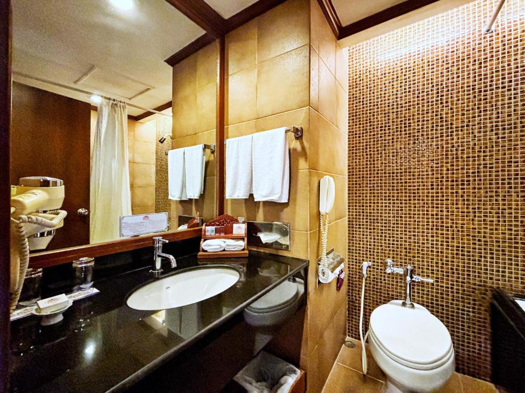 A compact marble-and-mosaic bathroom with a vanity, toilet and curtained shower area.