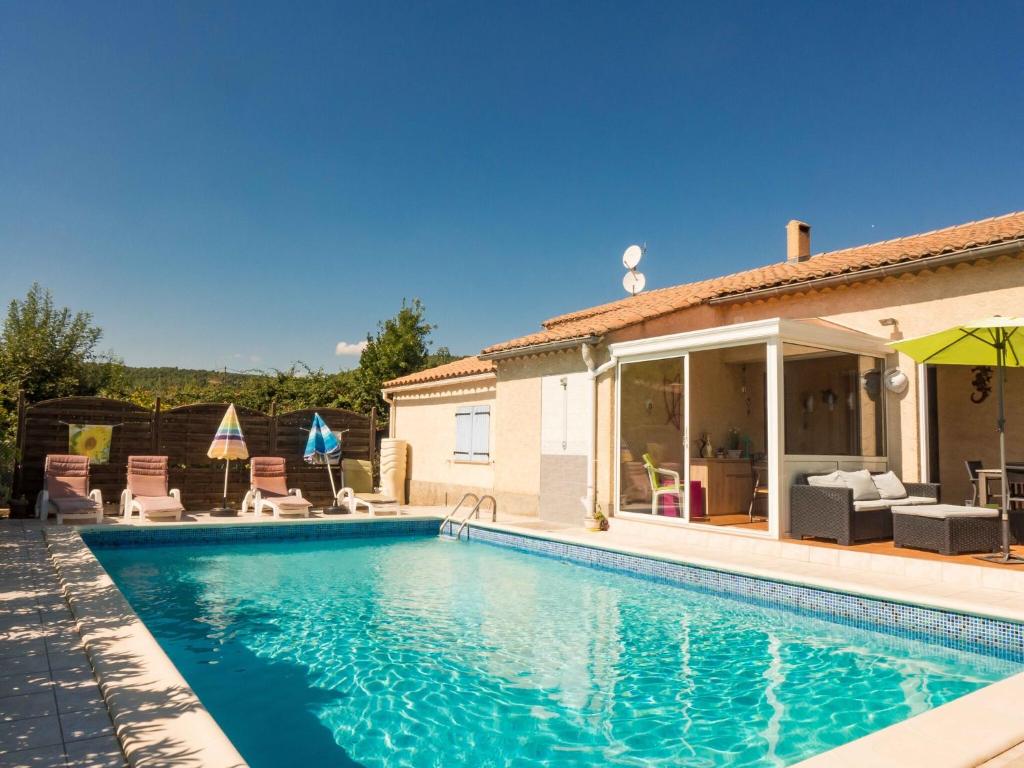 a swimming pool with chairs and a house at Peaceful Escape in Argeliers in Argeliers