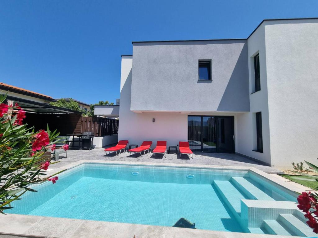a villa with a swimming pool and red chairs at villa Amethyst, private pool with heating and salt water in Lozenets