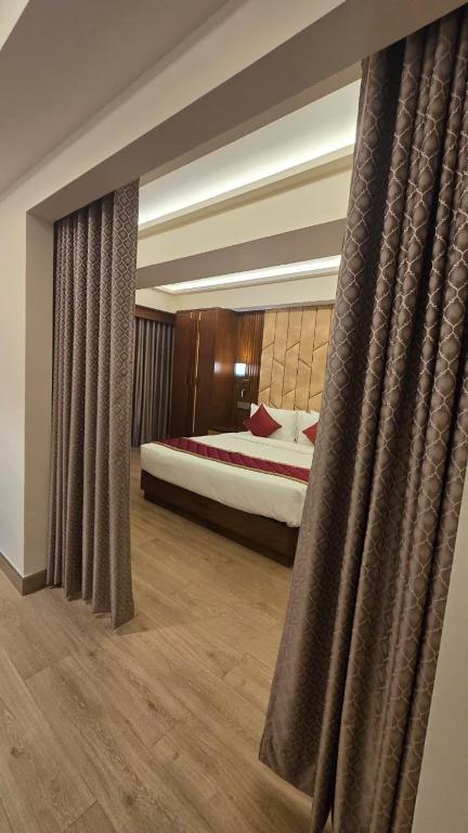 a bedroom with a bed and curtains in a room at Hotel Pentagon in Ettumānūr