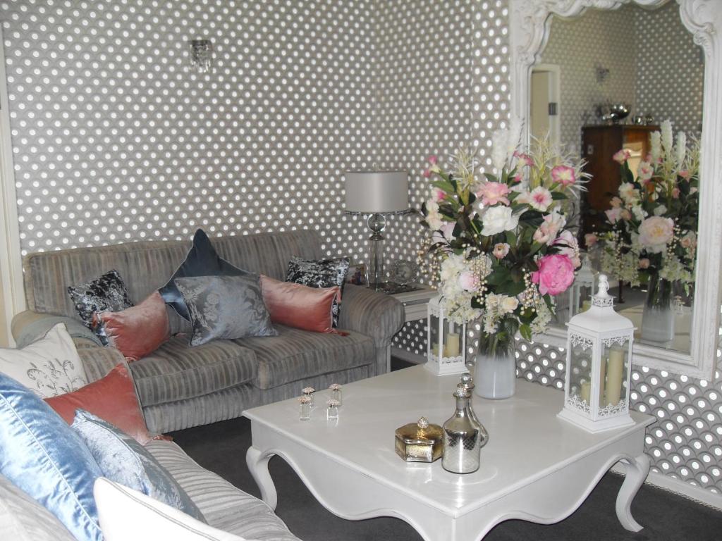 sala de estar con sofá y mesa con flores en Jessop House en Tewkesbury