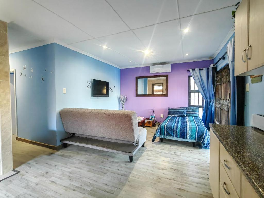 un soggiorno con pareti viola e divano di Swallows Rest Cottage KZN a Scottburgh