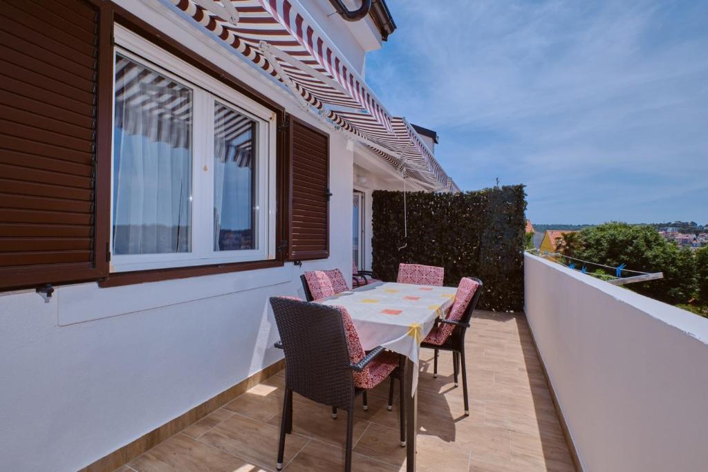 Un patio con una mesa y sillas en un balcón. en House Ruzica, en Mali Lošinj
