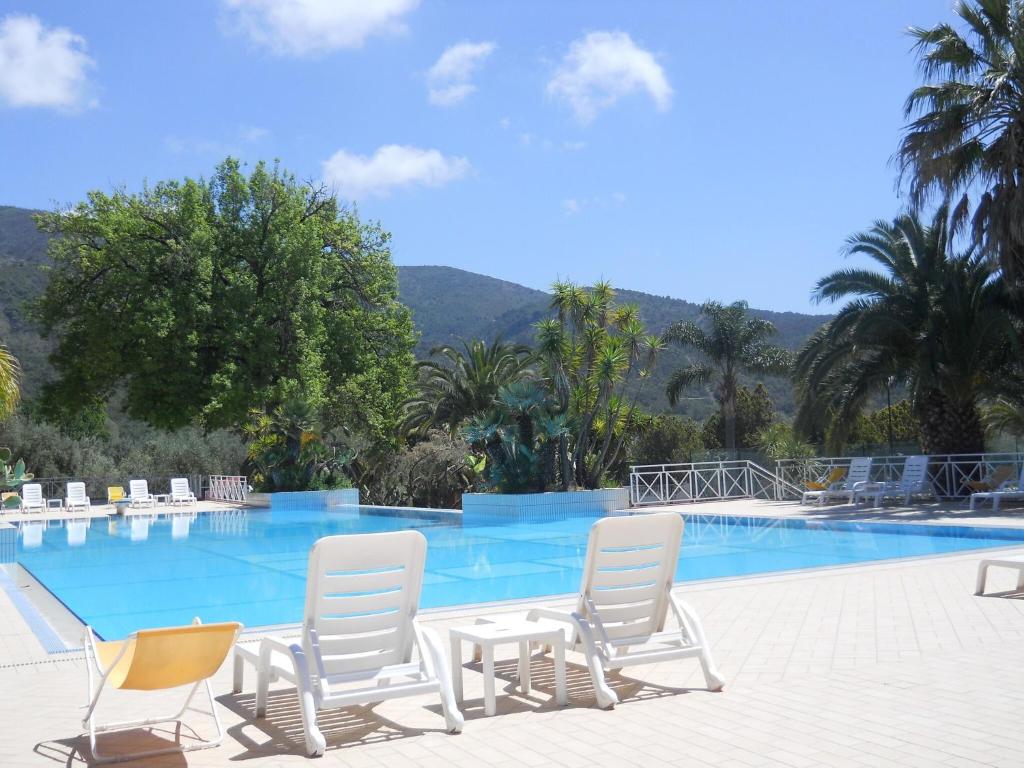 a swimming pool with white chairs and a table and a table and chairs at Luxurious Holiday Home in Palinuro Italy with Swimming Pool in Centola
