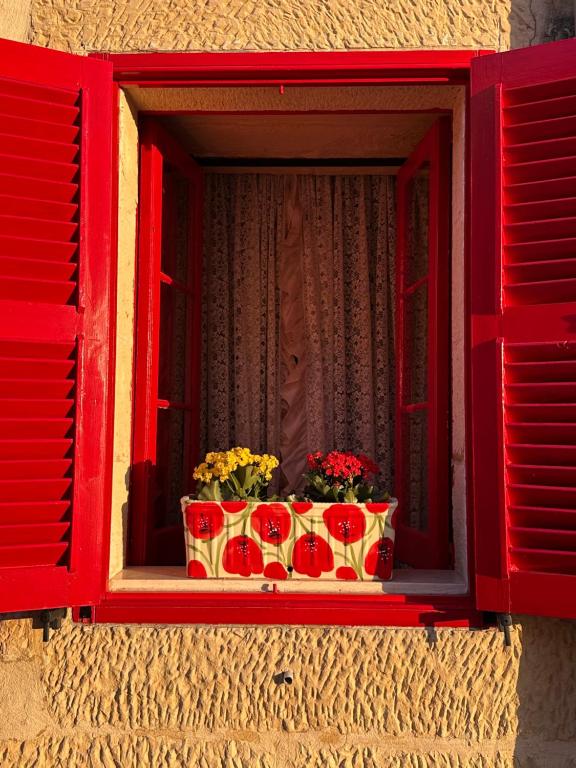 a red window with two flowers on a window sill at Traditional Holiday Home in the Heart of Nadur in Nadur