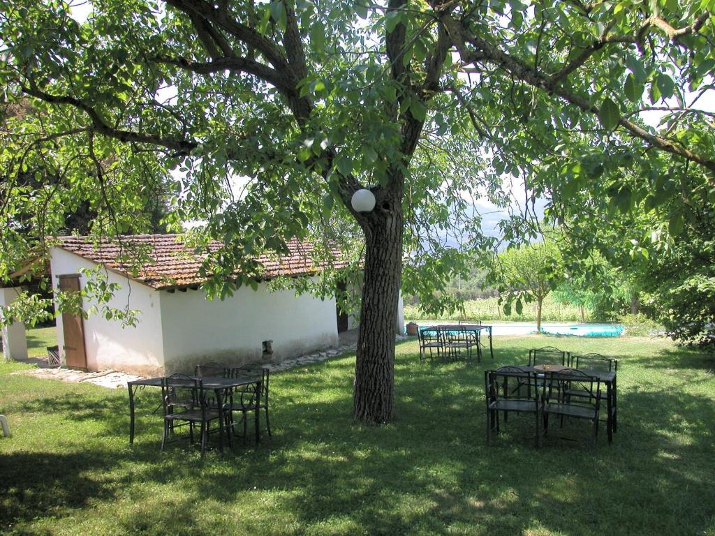 a group of tables and chairs under a tree at Attractive apartment in old farmhouse on the estate with pool in Umbertide