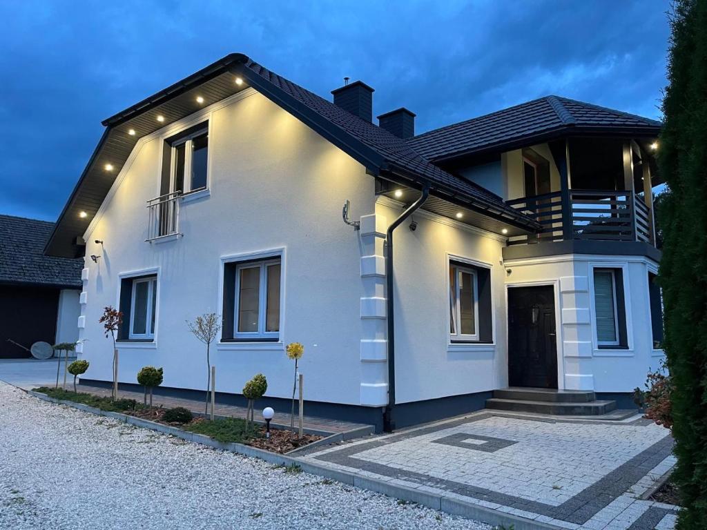 a white house with a black roof at Willa Apartament Prestige z sauną i siłownią na wyłączność in Żołynia