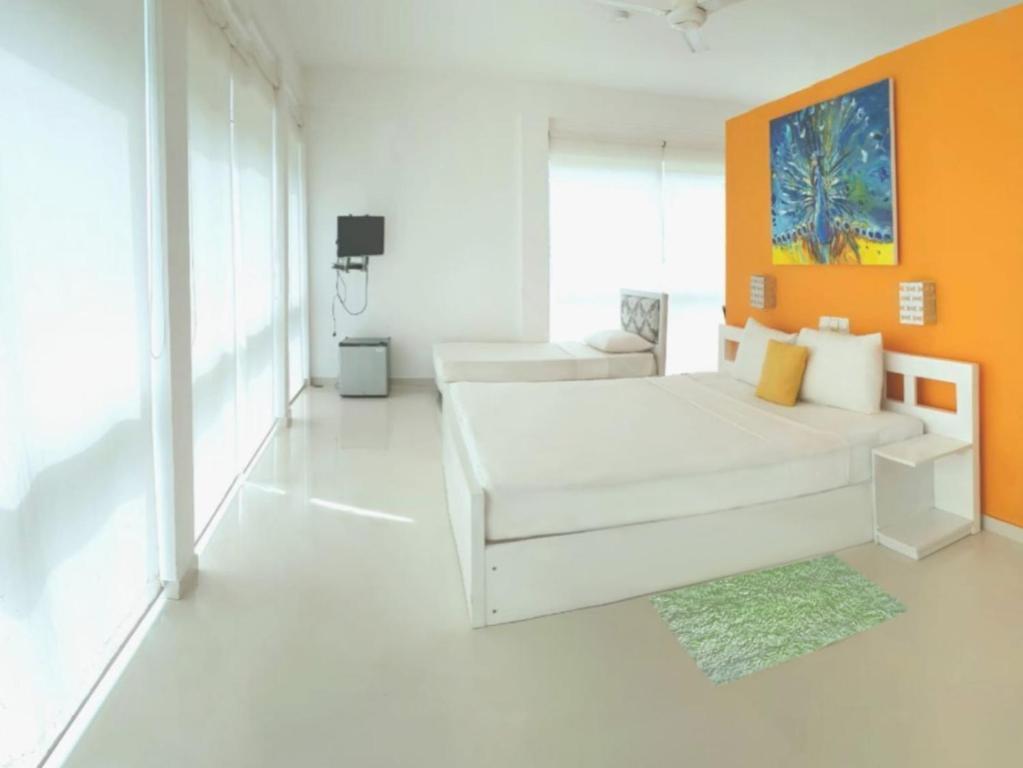 een witte kamer met een bed en een oranje muur bij Hotel Good Life Unawatuna in Unawatuna