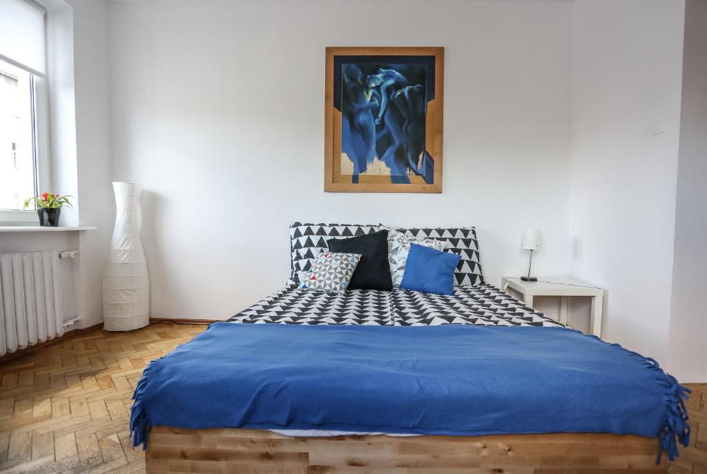 a bedroom with a large bed with blue sheets at Apartament Batory in Gdynia