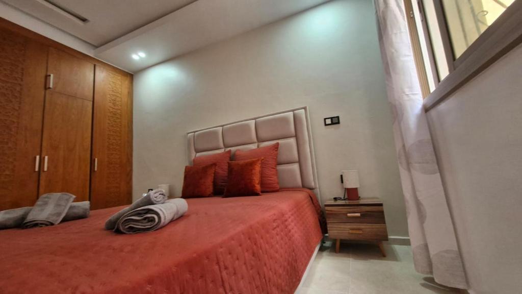 a bedroom with a bed with orange sheets and a window at Appart familial, fibre50 mbps parking,ipptv in Kenitra