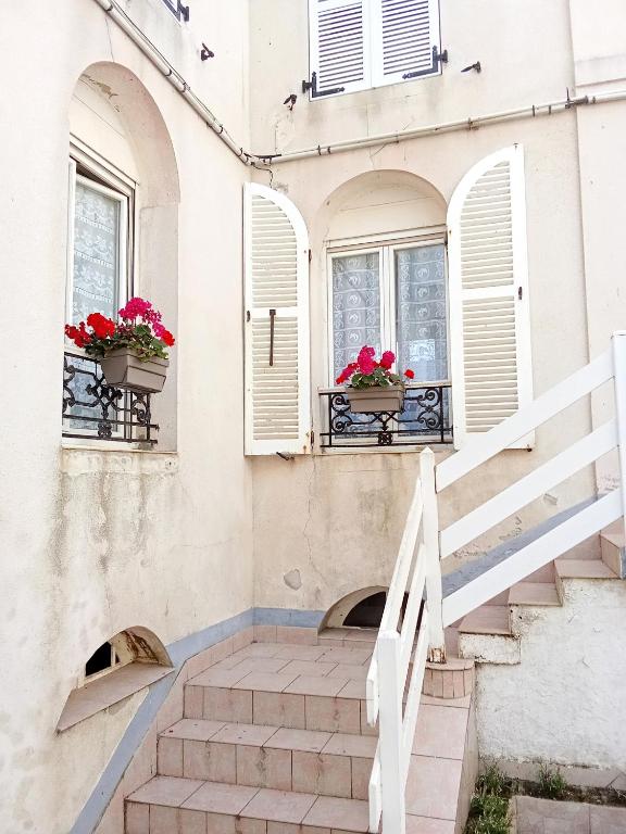 a house with flowers on the windows and stairs at LE GOELAND in Ault
